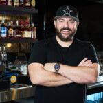 Chris Young leaning on a bar and smiling for a portrait.