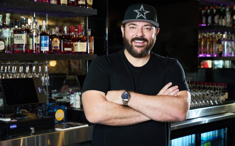Chris Young leaning on a bar and smiling for a portrait.