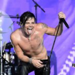 Yungblud smiles while holding a microphone during a live performance