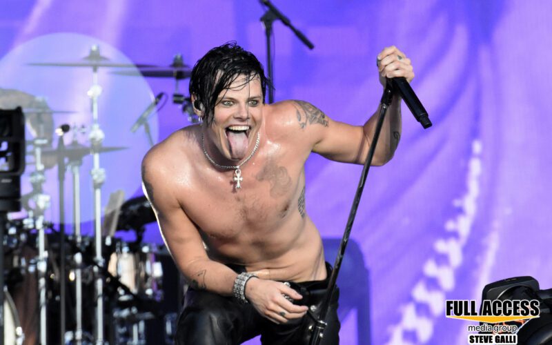 Yungblud smiles while holding a microphone during a live performance