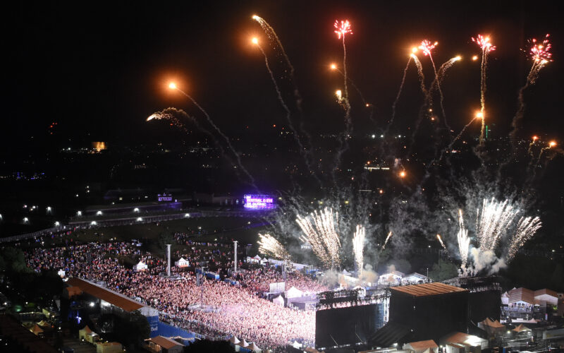 Fireworks rise above the Bell Stage and a large festival crowd