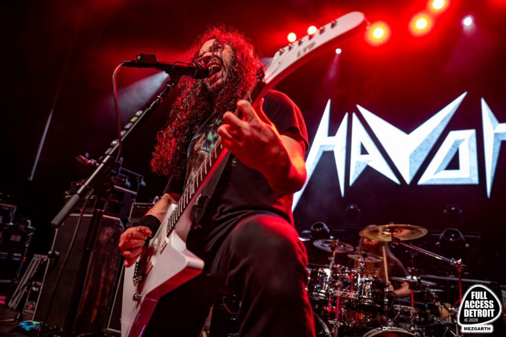 Havok singer playing a white guitar beneath red stage lights