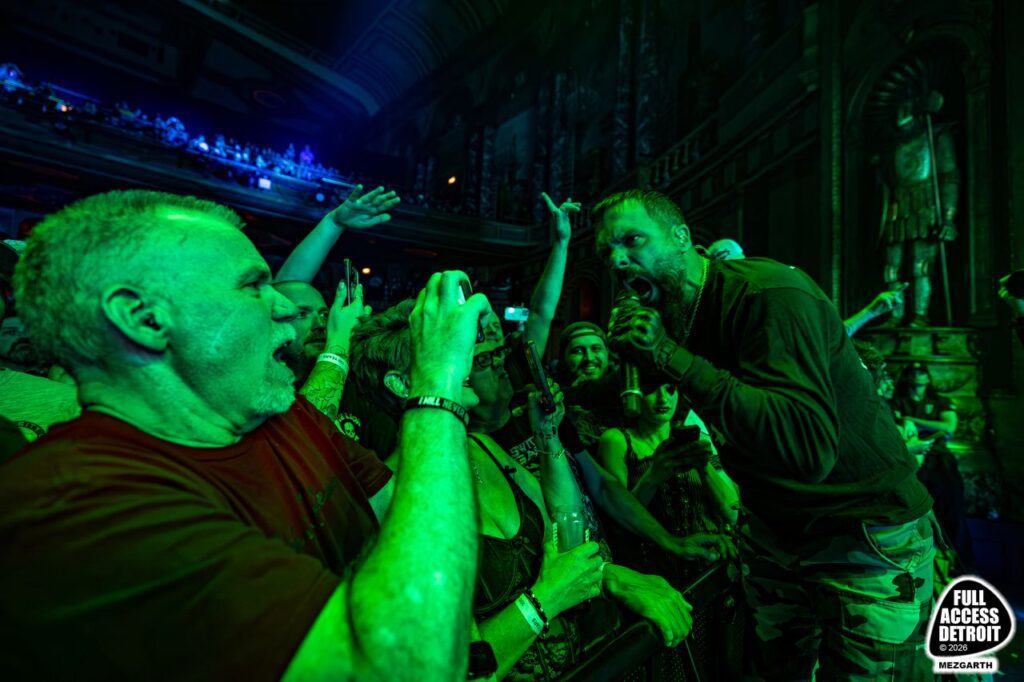 Killswitch Engage singer leaning toward a fan and camera at the stage barrier