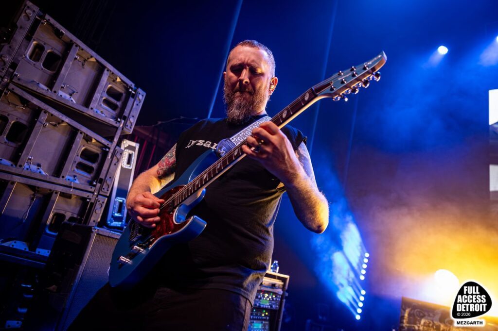 Killswitch Engage guitarist playing under blue and amber stage lights
