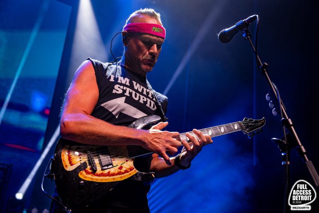Killswitch Engage guitarist performing in a red cap under blue lights