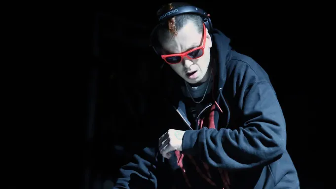 Slipknot's Sid Wilson wearing sunglasses against a dark background