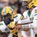 Football players in white and yellow uniforms during a play