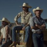 Midland band members in cowboy hats standing beside a yellow vehicle in the desert.