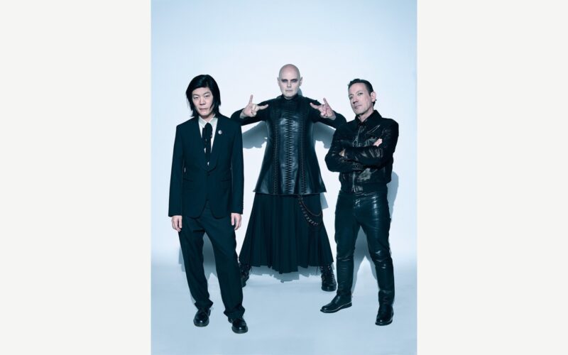 The Smashing Pumpkins posing together against a pale studio background.